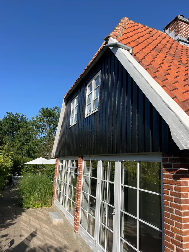Gavlen efter maling, med sort træbeklædning og afdækningen fjernet