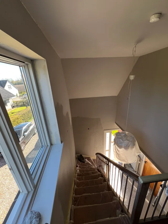 Trapperummets vægge og loft under forarbejdet med afdækket trappe og lampe